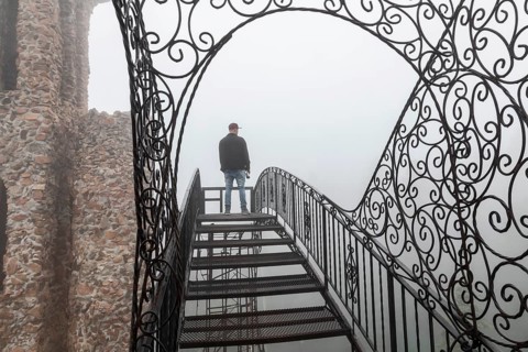 Rye, Colorado, A main stands on an open stairway, high above the ground, at Bishop Castle on a