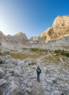 Mountaineer on a hiking trail, rocky mountain peaks Blaueisspitze and Hochkalter at sunrise,