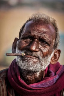 CHENNAI, INDIA, FEBRUARY 10, 2014: Unidentified old fisherman smoking on Marina beach in Chennai,