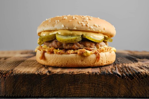 Beef burger with pickled cucumber and onion crumbs front view