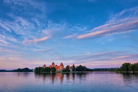 Trakai Island Castle in lake Galve, Lithuania on sunset with dramatic sky reflecting in water.