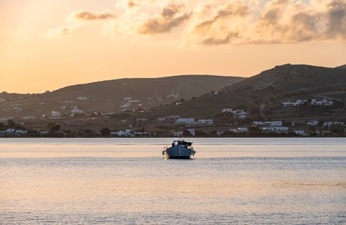 Fishing boat on the sea, behind hill of Paros island, Naoussa, Paros, Cyclades, Greece, Europe