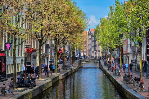 AMSTERDAM, NETHERLANDS, MAY 7, 2017: Amsterdam street with canal with old houses. Red lights