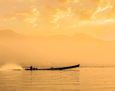 Speeding motor boat silhouette on Inle lake on sunset, Myanmar, Asia