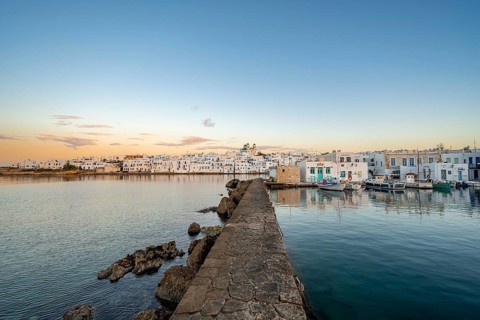 Harbour wall, view of the town of Naoussa and blue sea, at sunset, harbour with fishing boats and