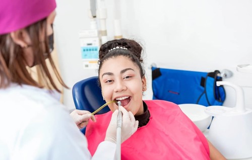 Stomatologist woman with drill cleaning patient girl mouth. Stomatologist drilling and cleaning a