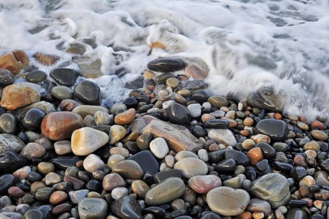 Colourful water smoothed pebbles in surf at shingle beach, Normandy, France, Europe