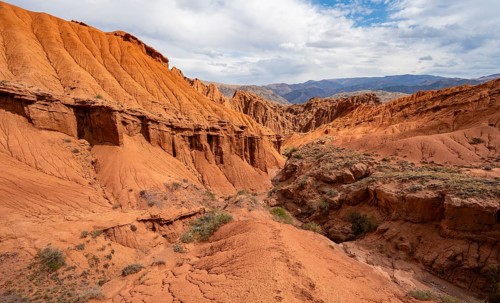 Eroded mountain landscape with sandstone cliffs, canyon with red and orange rock formations,