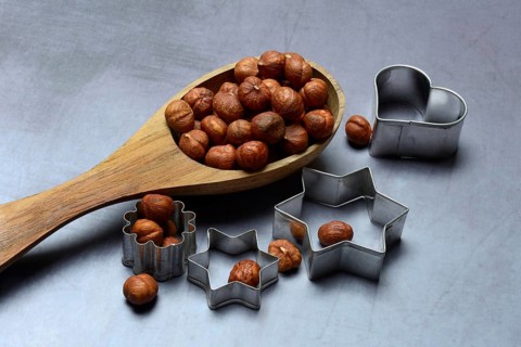 Wooden ladle with hazelnuts, cookie cutters, baking ingredient