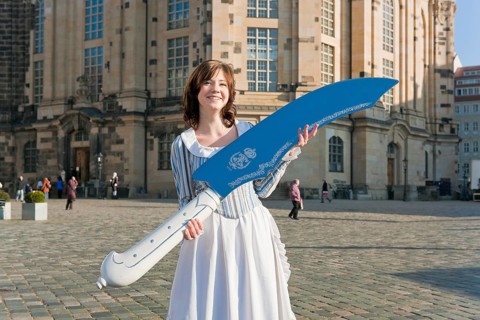 Stollen girl Lisa Straßberger presents the giant stollen knife in front of the Church of Our Lady