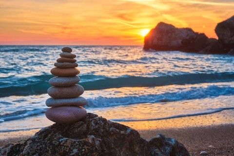 Cairn stack of stones pebbles cairn on the beach coast of the seaon sunset. Agios Ioannis beach,