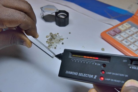 Diamond dealer inspecting a diamond for its authenticity, Koidu, Koidu-Sefadu, Kono District,