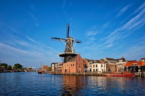 Harlem cityscape, landmark windmill De Adriaan on Spaarne river with boats. Harlem, Netherlands