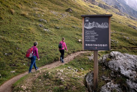 Two hikers, shield, Odle, Geisler peaks, Puez-Odle nature Park, Seceda, Val Gardena, Trentino,