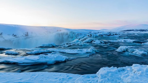 Icefall at the edge of the Godafoss waterfall at dawn, snow-covered landscape, Northern Iceland