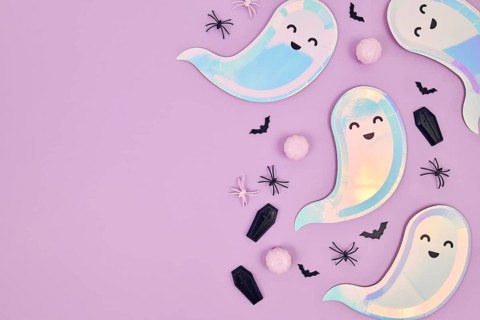 Cute pastel colored Halloween party flat lay with ghost shaped plates, spiders, pumpkins and