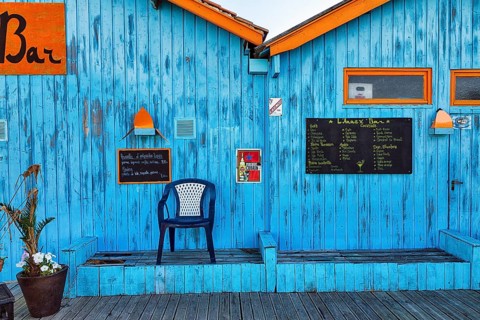 Colourful hut, wooden facade of a bar with orange sign and menu, advertising alcoholic beverages,