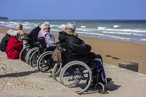 Elderly people in wheelchairs watching the sea on a cold day