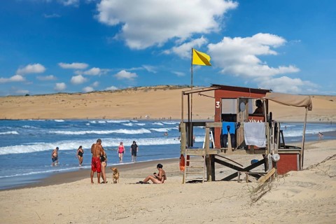 Lifeguard tower and tourists walking on the beach at Barra de Valizas, seaside resort, balneario