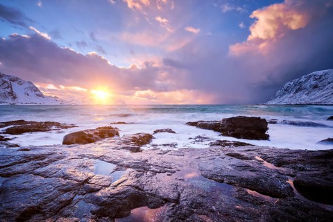 Beach of Norwegian sea on rocky coast in fjord on sunset in winter. Vareid beach, Lofoten islands,