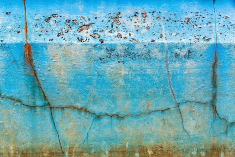 Dirty broken wall in a swimming pool, cracks, peeling blue colour, dilapidated swimming pool, lost