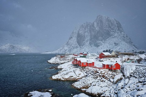 Iconic Hamnoy fishing village on Lofoten Islands, Norway with red rorbu houses. With falling snow