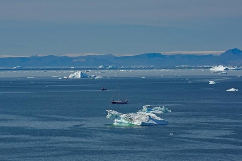 Sailboat in a bay covered with icebergs, Disko Island in the background, Ilulissat, Arctic, Disko