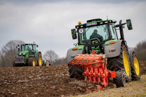Tractor with a plough preparing the soil of a field for planting, Agriculture, Spring