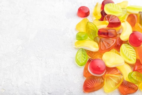Various fruit jelly candies on gray concrete background. side view, copy space