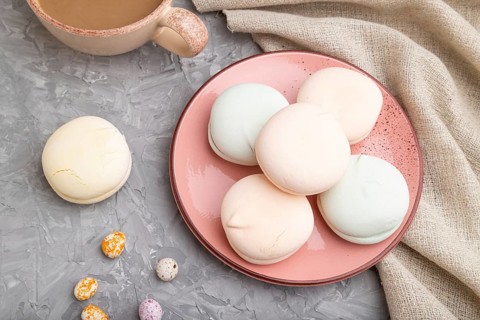 Colored zephyr or marshmallow with cup of coffee and dragees on a gray concrete background and
