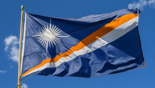 The flag of the Marshall Islands, Pacific Islands, flutters in the wind, isolated against a blue