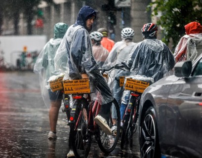 Tourists on a Berlin On Bike cycling tour protect themselves from heavy rainfall with rain capes,