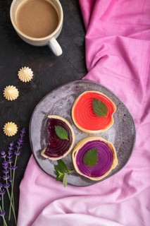 Sweet tartlets with jelly and milk cream with cup of coffee on a black concrete background and pink
