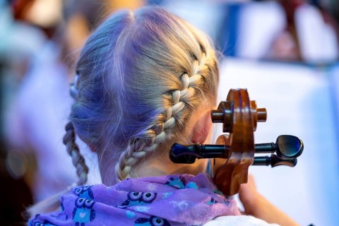 Young girl plays a cello at a concert