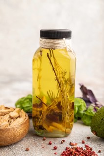 Sunflower oil in a glass jar with various herbs and spices, sesame, rosemary, avocado, basil,