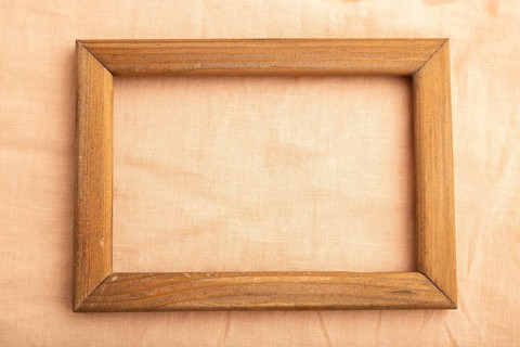 Wooden frame on smooth orange linen tissue. Top view, flat lay, natural textile background and