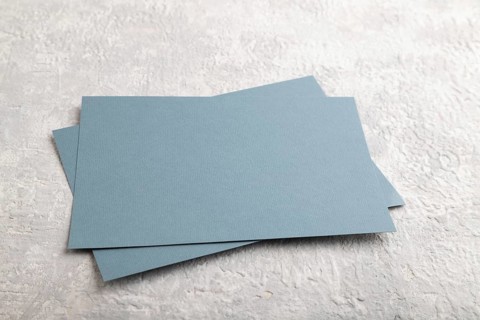 Blue paper business card, mockup on gray concrete background. Blank, side view, still life, copy