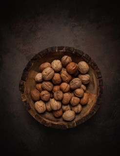 Fresh walnut in a shell, wooden plate, top view, no people