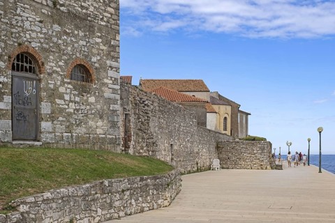 Tourists walking on promenade along ancient city wall in the town Pore?, Parenzo, seaside resort at