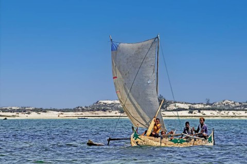 Malagasy fishermen sailing in traditional wooden fishing boat, outrigger canoe on the Indian Ocean,