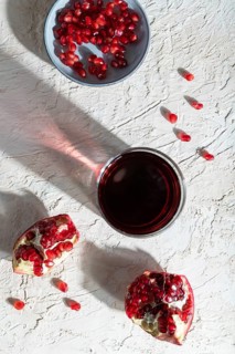 Glass of pomegranate juice on a white concrete background. Hard light, contrast. Top view, close