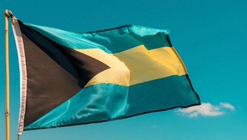 The flag of the Bahamas flutters in the wind, isolated against a blue sky