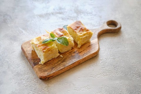 Overhead view of three pieces of Georgian cheese pie Achma on wooden cutting board