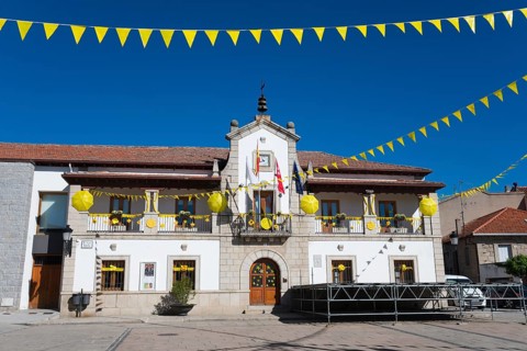 Historic building on a sunny square with yellow flags and festive decorations under a blue sky,