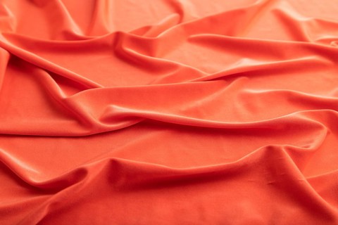 Fragment of red silk tissue. Side view, natural textile background and texture. wave concept,