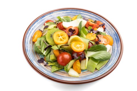 Vegetarian salad of pac choi cabbage, kiwi, tomatoes, kumquat, microgreen sprouts isolated on white