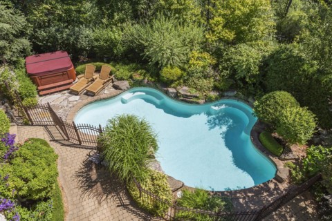 Top view of in-ground swimming pool surrounded by copper coloured wrought iron metal security fence
