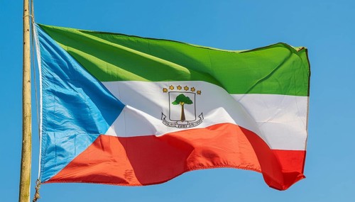 The flag of Equatorial Guinea flutters in the wind, isolated against a blue sky