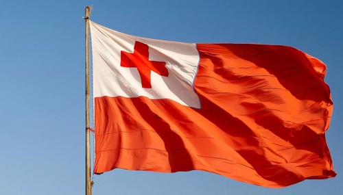 The flag of Tonga, Pacific island state, flutters in the wind, isolated against a blue sky