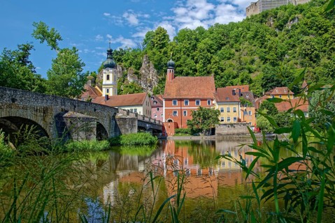 Ancient stone bridge over the river Naab with the church tower of St Michael and the leaning tower